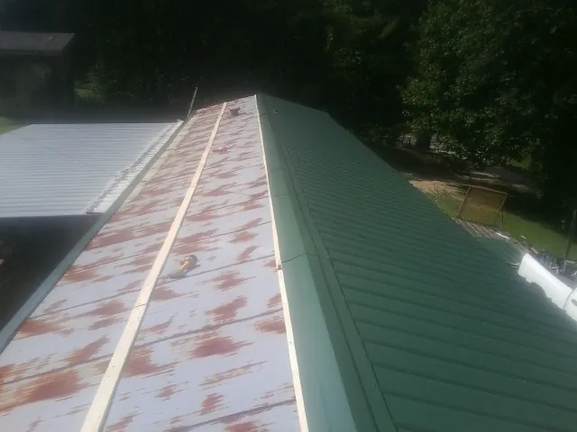 Old rusted panels beside newly installed green metal roofing — Wind Damage Roof Repair by Roofing Brothers in Hixson