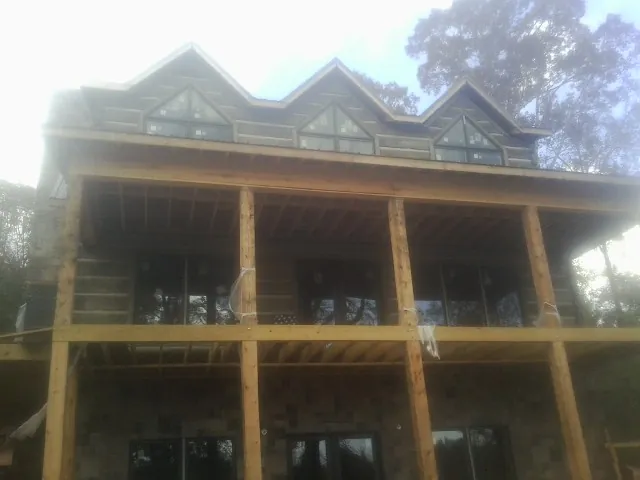 Dormers and porch framing on a large log home under construction — Roof Coating work by our crew in Hixson
