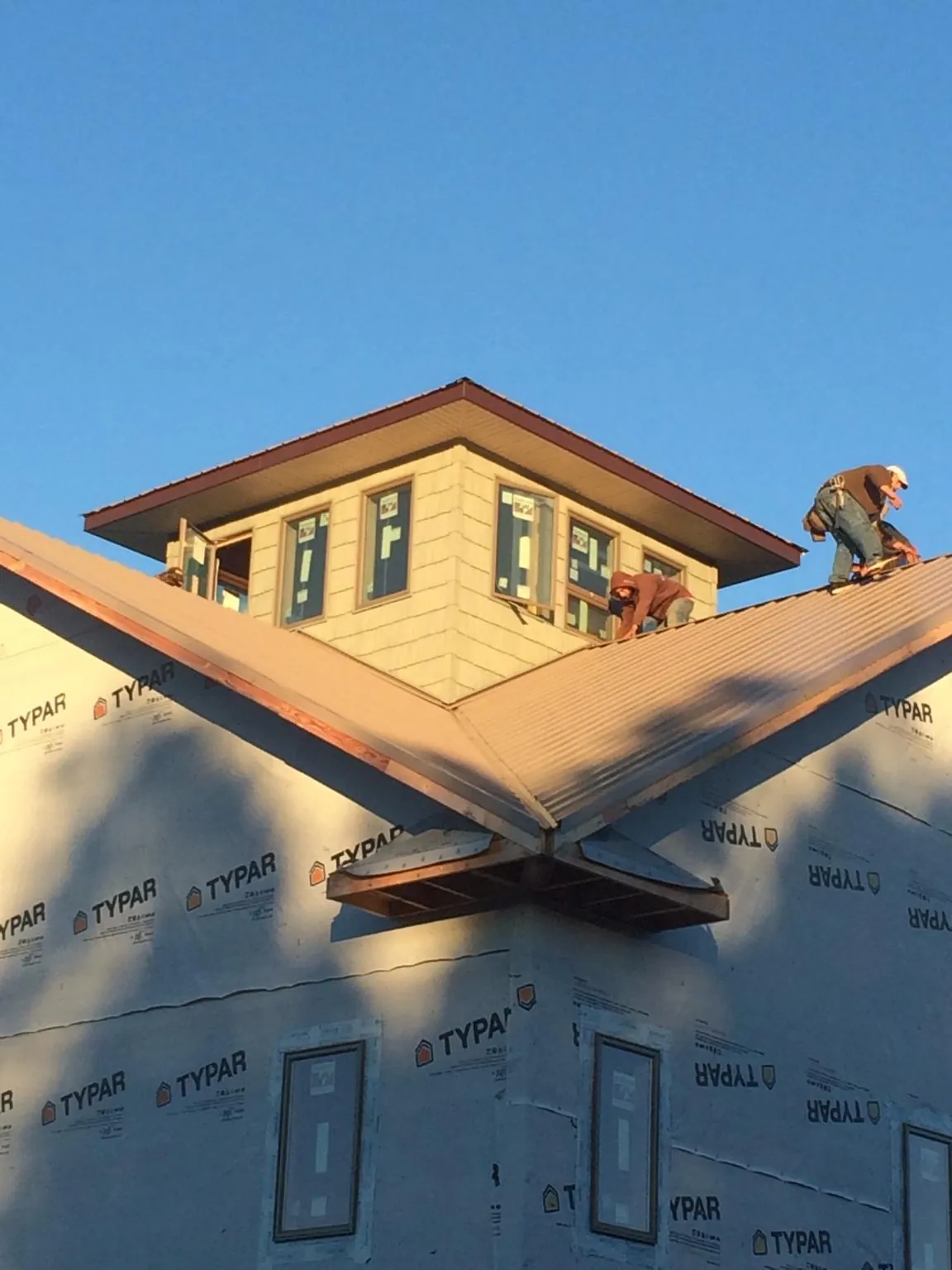 Roofers working around a rooftop cupola on a new metal roof at sunset — Roof Waterproofing in Hixson by Roofing Brothers